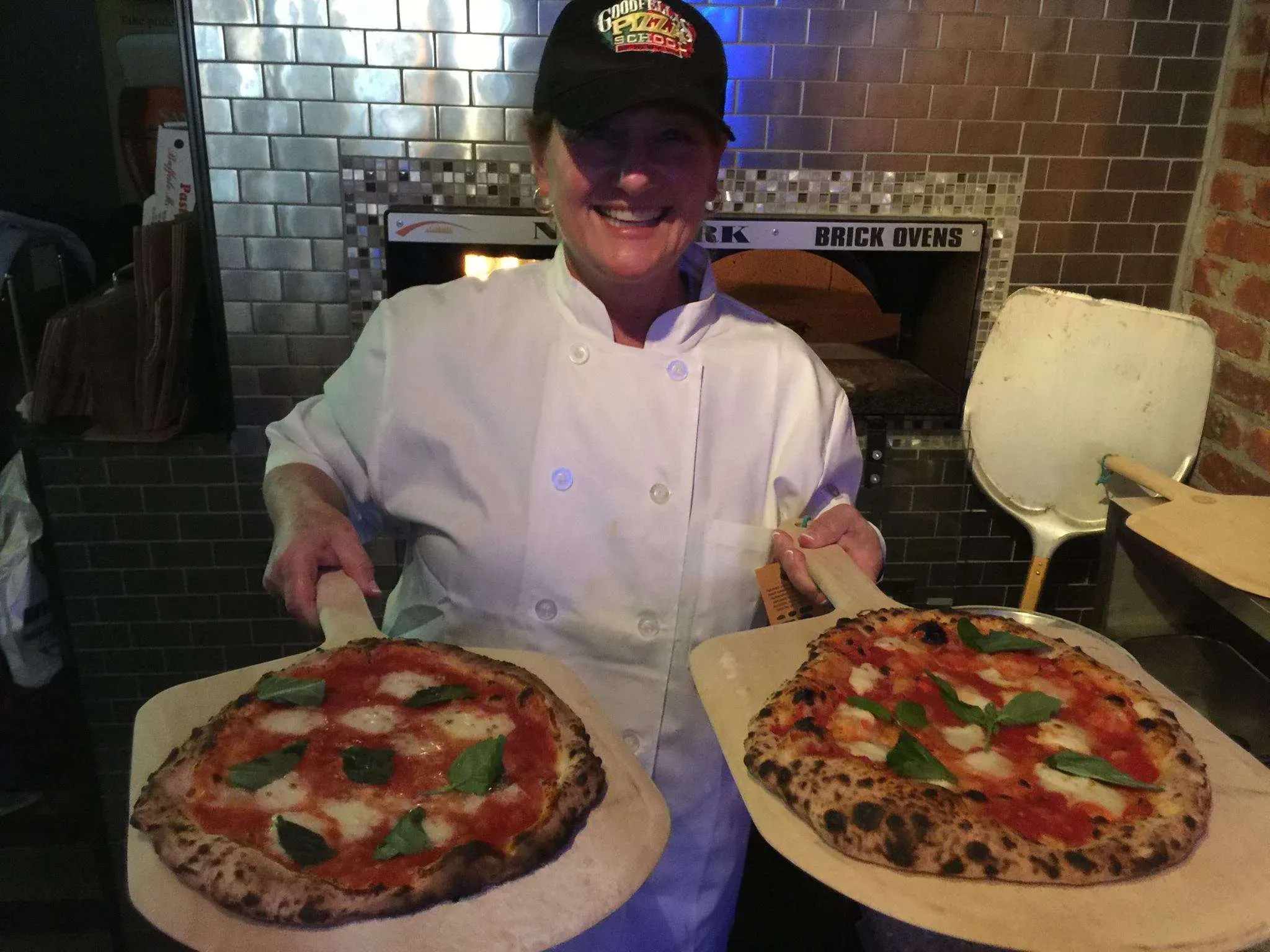 pizza making student holding two pizzas